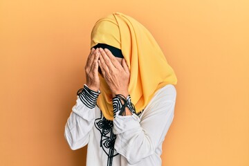 Poster - Middle age hispanic woman wearing traditional islamic hijab scarf with sad expression covering face with hands while crying. depression concept.