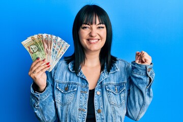 Sticker - Young hispanic woman holding peruvian sol banknotes screaming proud, celebrating victory and success very excited with raised arm