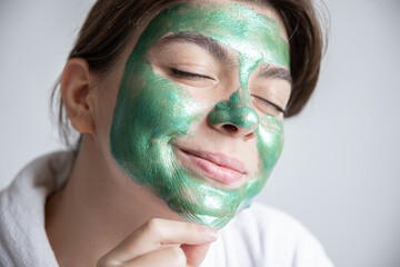 Wall Mural - Attractive young woman with a green cosmetic mask on her face.