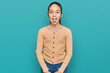 Beautiful brunette little girl wearing casual sweater sticking tongue out happy with funny expression. emotion concept.