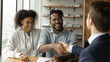 © fizkes - Happy African American family couple shaking hands with professional real estate agent broker lawyer financial advisor, thanking for professional consultation, celebrating making deal in office.