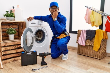 Poster - Young indian technician working on washing machine looking stressed and nervous with hands on mouth biting nails. anxiety problem.