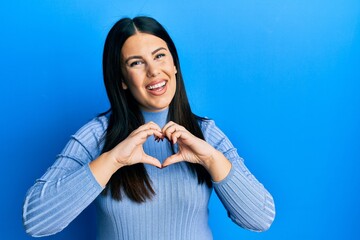 Poster - Beautiful brunette woman wearing casual clothes smiling in love doing heart symbol shape with hands. romantic concept.