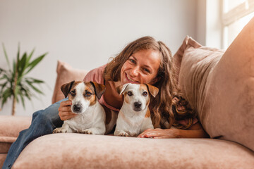 Poster - Happy girl with a dog is resting at home on the couch