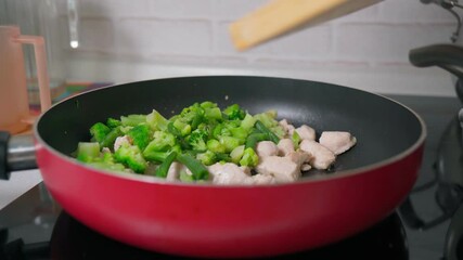 Wall Mural - Cooking chicken fillet with broccoli in a frying pan, selective focus