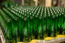 Glass Factory, Industrial Production Of Glass Containers. A Lot Of Empty Glass Bottles As A Background Of Green Glass Containers With Copy Space. Bottles For Drinks. Technological Work At The Factory.