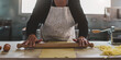 Closeup female hands roll the dough preparing fresh homemade pasta