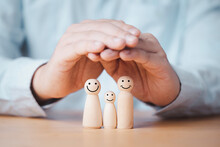 Business Hand Gesture Protecting Wooden Family Dolls For Insurance And Assurance Concept.