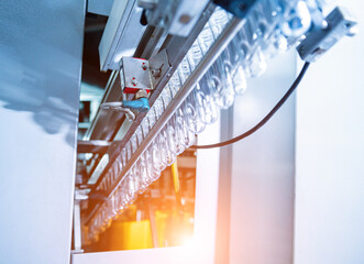 Wall Mural - Automatic filling machine pours water into plastic PET bottles at modern beverage plant.