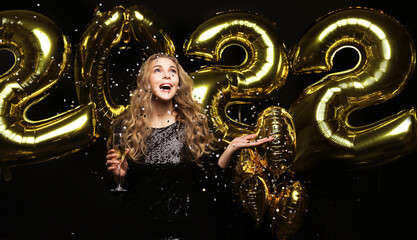 Wall Mural - Happy gorgeous girl in stylish sexy party dress holding gold 2022 balloons, having fun at Christmas or New Year's Eve Party.