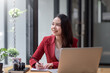 © amnaj - Smiling young Asian businesswoman is happy to work at the modern office using a laptop computer.