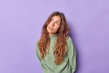 Wall Mural - Pretty brunette young European woman concentrated above with thoughtful expression poses against purple background recalls something in mind tries to remember her childhod. People and thoughts