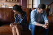 © fizkes - Family conflict. Frustrated married couple sit on couch after quarrel avoid talking look down suffer of offense misunderstanding. Upset young spouses ignore each other come through marriage problem