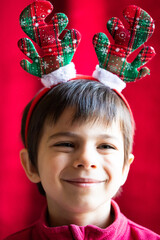 Wall Mural - Portrait of funny little smiling boy in headband of Christmas deer 