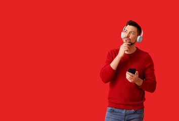 Canvas Print - Thoughtful man with phone and headphones on color background