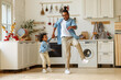 © JenkoAtaman - Happy african american family father and little son dancing to music in modern kitchen at home