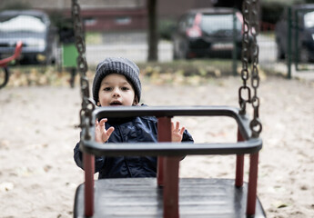 Canvas Print - Cute little caucasian boy by a swing in a playground