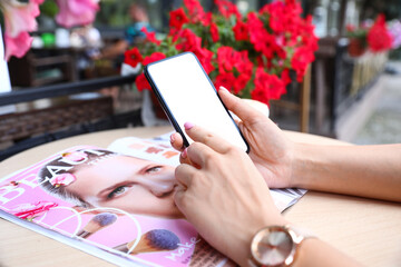 Sticker - Female hands with mobile phone and magazine on table in cafe