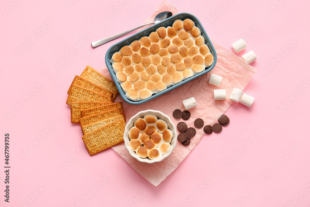 Baking dish and ramekin with tasty S'mores dip on pink background