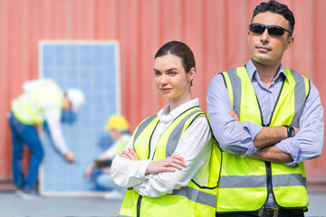 Group of Diversity factory worker people man and woman standing in front of containers logistic in warehouse. Worker staffs checking solar cell panel for renewable energy construction.