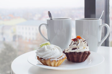 ywo cupcakes and two cups on table in cafe