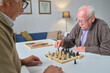 © pressmaster - Senior man making checkmate while playing chess together with his friend at the table