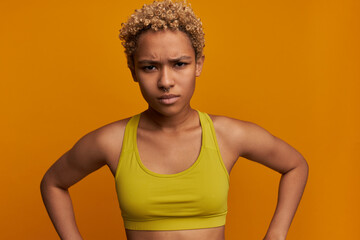 Wall Mural - Discontent, annoyed, strict face of sporty beautiful African American youthful blonde woman with short curls, looking at camera with dissatisfied, frowning expression. Negative human emotions