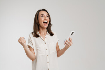 Wall Mural - Young woman making winner gesture and using cellphone