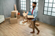 © Halfpoint - High angle view of happy young man holding packing boxes moving home, new living concept.