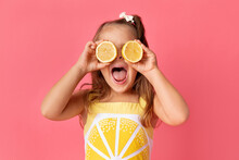 Funny Young Girl On Pink Background Holding Lemons Against Her Eyes