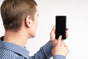 Poster - Man phone. Smartphone is turned off in hands of man. Man holds phone in front of him. Guy on white background, his back to camera. Businessman runs his finger on cellphone. Place to showcase apps