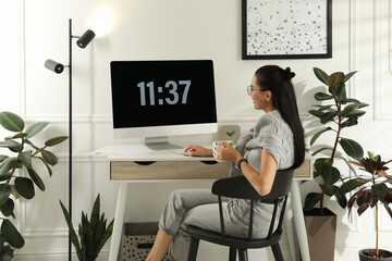 Wall Mural - Young woman with cup of tea working at table in light room. Home office