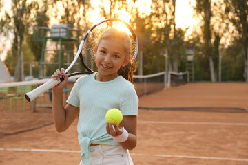 Wall Mural - Cute little girl with tennis racket and ball on court outdoors