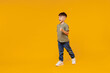 © ViDi Studio - Full body side view little small smiling happy boy 6-7 years old wearing green t-shirt walk go strolling isolated on plain yellow background studio portrait Mother's Day love family lifestyle concept