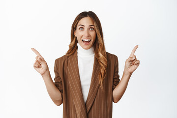 Excited middle aged saleswoman pointing sideways, corporate lady showing two choices, products against blank empty spaces, white background