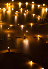 Wall Mural - christmas, holidays and illumination concept - close up of electric garland lights in darkness