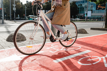 traffic, city transport and people concept - woman cycling along red bike lane with signs of bicycles on street