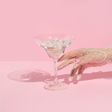 Creative Layout With Hand In White Lace Glove  Raeching Martini Cocktail Glass With Diamonds And Pearls On Pastel Pink Background. 80s Or 90s Retro Aesthetic Fashion Concept. Romantic Drink Idea.