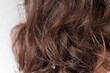 Close up of curly hair of a brunette woman. Brown laid curls of a young girl back view, beauty background with a hairstyle.