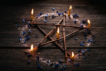 Wall Mural - Branch Pentagram - witchcraft tools of natural wood. Wooden pentagram with candles, small stones and petals of delphinium. Occultism and mysticism