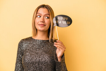 Wall Mural - Young caucasian woman holding new year props isolated on yellow background