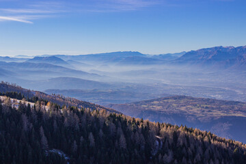 Wall Mural - Winter landscape of the Italian mountains. View of the Belluno Dolomites from Nevegal. Mountains with light haze illuminated by the sun. Climate change concept.