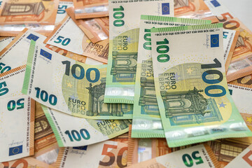 new 50 euro banknotes are scattered on the table and on them lie acuranto 100 euro banknotes