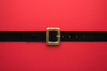 Creative Christmas Composition. Overhead Flat Lay View Photo Of Santa Claus And Black Belt With Golden Buckle On Bright Color Red Backdrop