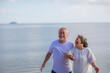 © sutthichai - An Asian couple walking together on the beach. Retirement and holiday concept.