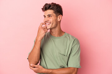 Young caucasian man isolated on pink background relaxed thinking about something looking at a copy space.