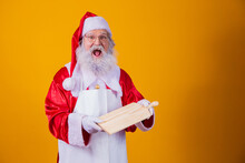 Santa Claus Dressed In Apron Holding Empty Meat Board On Yellow Background.