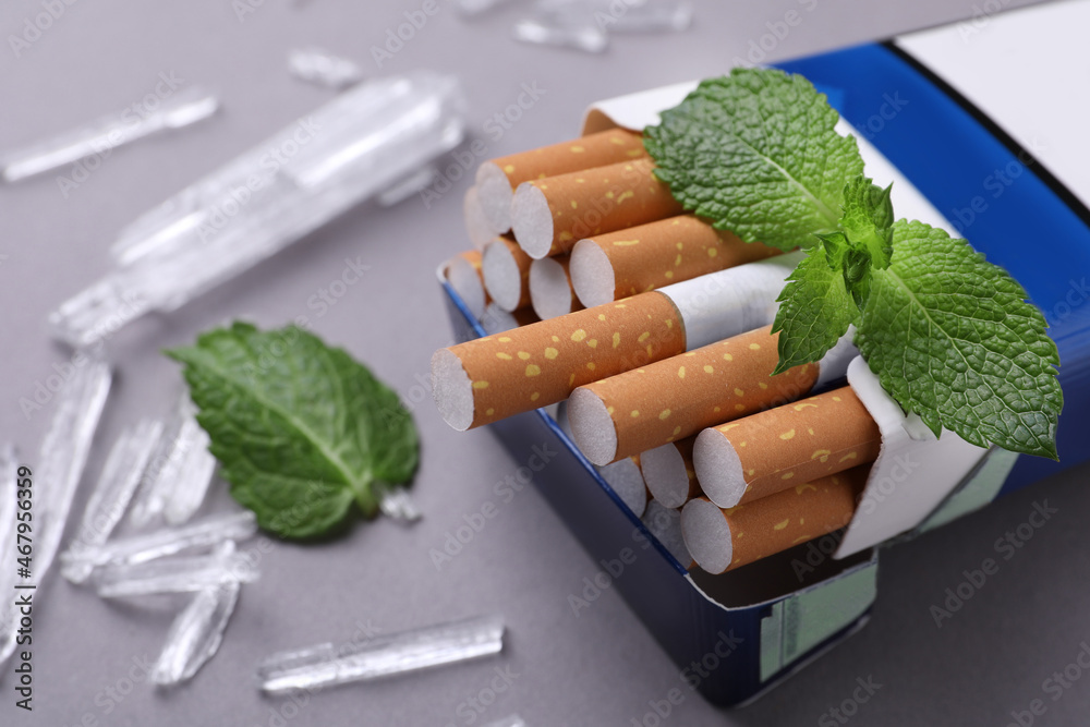 Pack of cigarettes, menthol crystals and mint leaves on grey background,  closeup Stock Photo