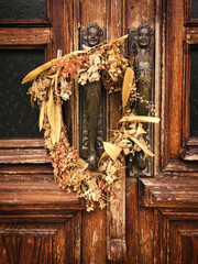 2 brass statues and a wreath of dried flowers on an old wooden door