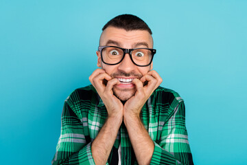 Wall Mural - Photo of unhappy upset scared shocked young man bite fingers wear glasses horrified isolated on blue color background
